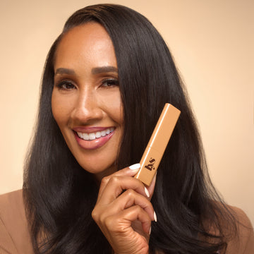 Woman holding a LYS Skin Tint product against a beige background